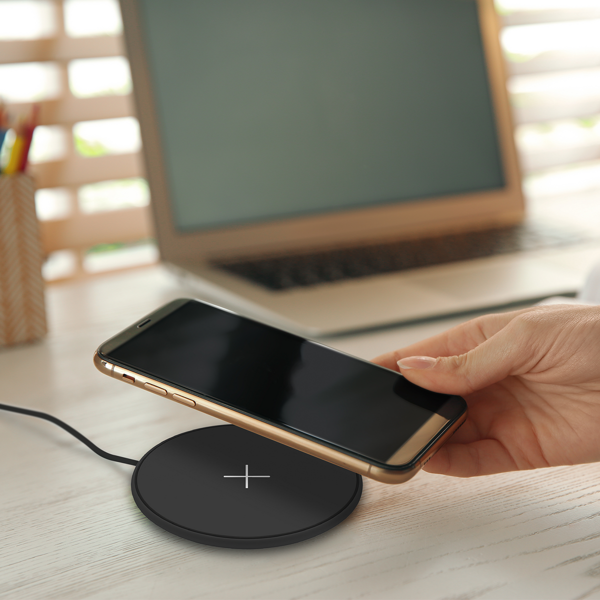 Phone being placed on the black Juice 10W wireless charging pad at a desk